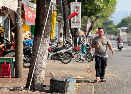 Một người dân sử dụng lòng đường để đi bộ vì phần vỉa hè đường Bạch Đằng, đoạn qua chợ Hàn bị chiếm dụng gần hết