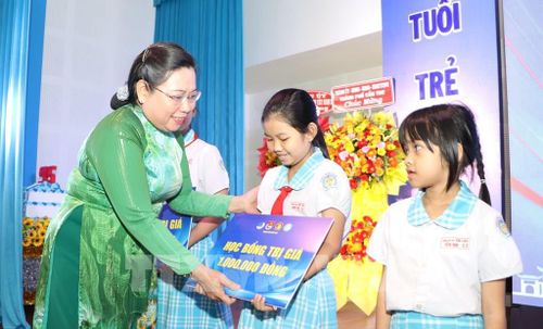 Lãnh đạo thành phố trao bảng tượng trưng học bổng cho học sinh có hoàn cảnh khó khăn. Ảnh: Hồng Thái - TTXVN