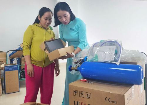 Chị Võ Thị Hiền (bên trái) vui mừng nhận máy thở điều trị cho con do các nhà hảo tâm tặng. Ảnh: N.Q