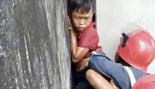 Tổ cứu nạn cứu hộ cẩn thận di chuyển bé trai ra khỏi khe hẹp giữa 2 căn nhà.