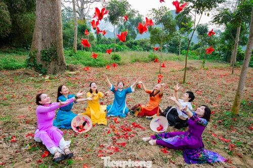 Dưới những tán gạo đỏ rực, du khách thoải mái thả dáng, say sưa ghi lại khoảnh khắc đẹp đã góp phần làm nên một không gian sống động mà vẫn đậm chất bình yên. Tất cả hòa quyện tạo nên một bức tranh làng quê vừa gần gũi, vừa đầy sức sống. Ảnh: Rạng Đông