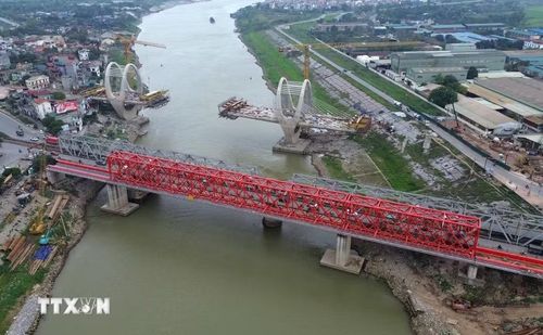 Bên cạnh đó cầu đường sắt (màu đỏ) bắc qua sông Đuống cũng được nhà thầu thi công khẩn trương. Sau khi hoàn thành đường bộ và đường sắt qua sông Đuống tách bạch. (Ảnh: Quốc Khánh/TTXVN)