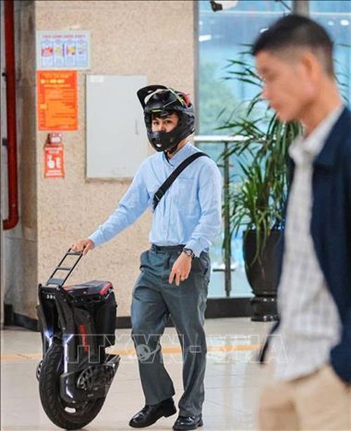 Một hành khách khi đi tàu điện trên cao còn chủ động kết hợp mang theo xe điện gấp gọn, nhằm linh hoạt cho quãng đường di chuyển tiếp theo, tối ưu hóa hành trình đi lại theo hướng thuận tiện và thân thiện với môi trường. Ảnh: Hoàng Hiếu/TTXVN