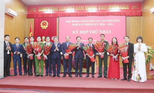 Các đại biểu tặng hoa chúc mừng lãnh đạo UBND xã khóa mới. Ảnh: Công Phương