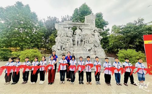 Học sinh Trường Tiểu học Đức Xuân cầm trên tay chiếc khăn quàng đỏ tại Khu di tích lịch sử Nà Tu.