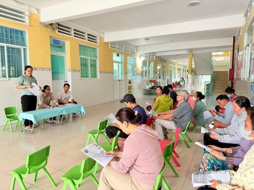  Nhân viên y tế xã Thái Mỹ hướng dẫn phụ huynh các biện pháp chăm sóc và phòng bệnh tay chân miệng cho trẻ tại trường Mầm non Phước Thạnh. Ảnh: HCDC. 