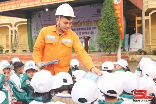 Công nhân Điện lực Mộc Châu - Vân Hồ phát tờ rơi tuyên truyền sử dụng điện tiết kiệm, an toàn cho học sinh.