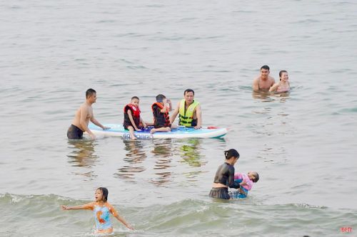 Du khách hòa mình vào làn nước xanh trong và tận hưởng những luồng gió mát lành từ khơi xa, xua tan cái oi nồng của những ngày nắng nóng đầu hè.