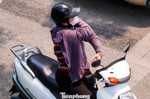 Một người phụ nữ đang lưu thông trên đường phải dừng lại để mặc thêm áo chống nắng.