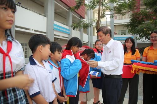 Nhà báo Nguyễn Khắc Văn, Quyền Tổng Biên tập Báo SGGP, trao áo khoác cùng học bổng đến các em học sinh tại xã Bình Lợi. Ảnh: DŨNG PHƯƠNG