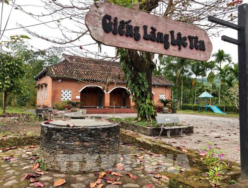 Giếng cổ và nhà đón tiếp du khách khi bước vào cổng làng Lộc Yên. Ảnh: Quốc Dũng - TTXVN