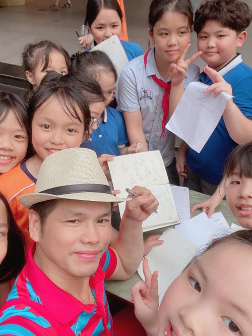 Các em học sinh vây quanh NSƯT Trần Quý Quốc xin chữ ký