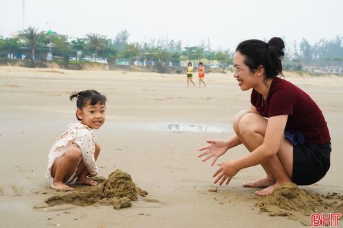 Sau khi tắm biển, nhiều người ở lại nghỉ ngơi, trò chuyện trên bãi cát trước khi trở về nhà. Trẻ nhỏ vui chơi, nô đùa tạo nên không khí sinh hoạt gần gũi.