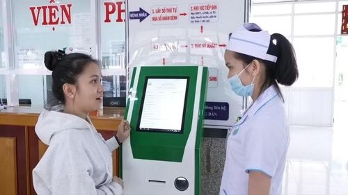 Nhân viên y tế Bệnh viện Nhi Gia Lai hướng dẫn người dân đăng ký khám - chữa bệnh trên Kiosk y tế thông minh. Ảnh: Hồng Quý