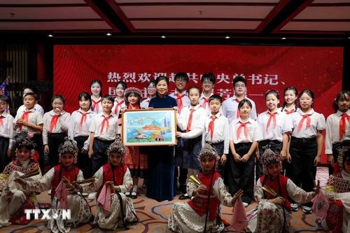  Phu nhân Ngô Phương Ly tặng quà cho các học viên của Trung tâm đã biểu diễn tiết mục Mộc Quế Anh quải soái để chào mừng. Đội hình thiếu nhi Việt Nam tham gia Hành trình Đỏ tại Bắc Kinh cũng góp mặt trong một tiết mục. Ảnh: TTXVN. 