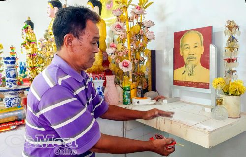 Ông Thạch Xia, ấp Tân Điền B (xã Thanh Tùng), cẩn trọng lau dọn bàn thờ Bác Hồ, từng động tác trang nghiêm như gói ghém cả sự tri ân nhớ Bác vào dịp tết của dân tộc. Ảnh: NGUYỄN ĐÀO