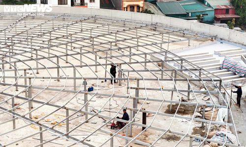Trên công trường, nhiều công nhân tập trung lắp dựng hệ khung thép trên mái, chuẩn bị cho các hạng mục hoàn thiện tiếp theo.