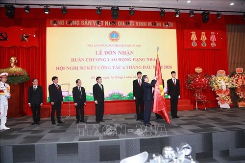 Bí thư Trung ương Đảng, Chánh án Tòa án nhân dân Tối cao Nguyễn Văn Quảng gắn Huân chương Lao động hạng Nhất lên lá cờ truyền thống của Tòa án nhân dân thành phố Hà Nội. Ảnh: Kim Anh/ TTXVN