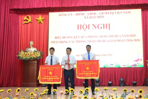 Chủ tịch UBND xã Hát Môn Lý Hoàng Kiên trao Cờ Đơn vị xuất sắc trong phong trào thi đua của thành phố cho các tập thể. Ảnh: NM