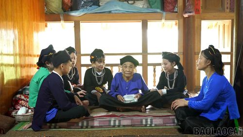 Học sinh xã Mường Lai quây quần bên nghệ nhân cao tuổi dưới nếp nhà sàn, học hát khắp cọi, trao truyền và gìn giữ bản sắc văn hóa dân tộc Tày cho thế hệ trẻ.