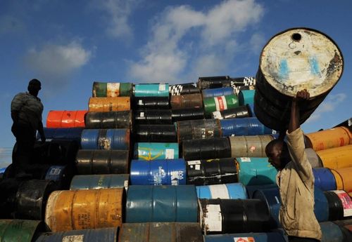 Hình ảnh chụp những người đàn ông đang xếp chồng các thùng dầu. Ảnh: Reuters.