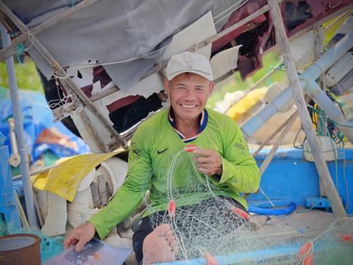 Ngư dân vá lại lưới chuẩn bị cho chuyến biển mới