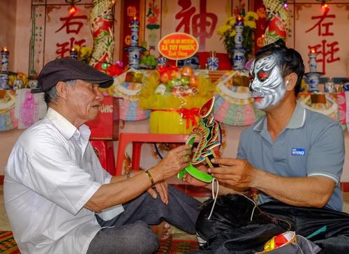 Nghệ nhân Ưu tú Hồ Thành Long (bìa trái) hướng dẫn một thành viên đội bả trạo chuẩn bị biểu diễn. Ảnh: N.N