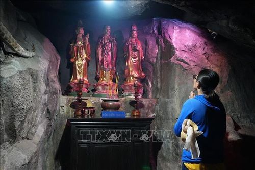 Du khách chiêm bái Tây phương Tam thánh trong hang động của Chùa Hang.