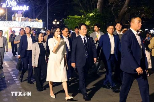 Tổng thống Hàn Quốc Lee Jae Myung và Phu nhân Kim Hae Kyung vừa ăn kem Thủy Tạ vừa đi dạo quanh hồ Hoàn Kiếm. (Ảnh: Phạm Kiên/TTXVN)