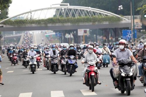 Người dân di chuyển dưới thời tiết nắng nóng, nhiều người trang bị khẩu trang, áo chống nắng để giảm tác động của nhiệt độ cao trong giờ cao điểm.