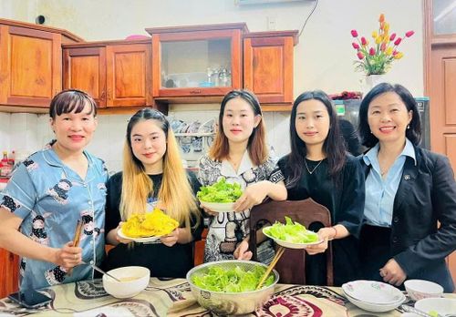 Những cô con gái người Lào của bà Thành học cách làm bánh xèo Việt Nam. Ảnh: NGUYỄN HỮU