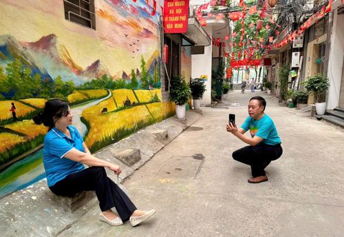 Vợ chồng ông Nguyễn Phúc Trung và bà Khiếu Thị Hằng tranh thủ chụp ảnh với bức tranh tường. Ảnh: Bảo Lâm