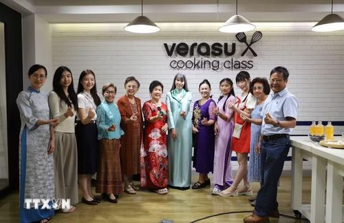 Phu nhân Hồ Thị Thu Trang (áo dài xanh ngọc) chụp ảnh lưu niệm cùng bà con kiều bào tại chương trình. (Ảnh: Đỗ Sinh/TTXVN)