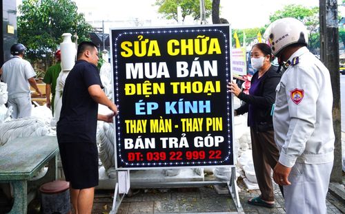 Lực lượng chức năng phường nhắc nhở người dân tự giác sắp xếp biển hiệu, dành vỉa hè cho người đi bộ. Ảnh: NGỌC HÀ
