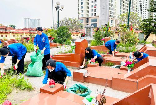 Các bạn trẻ nhổ cỏ và làm sạch các phần mộ. Ảnh: Trần Oanh