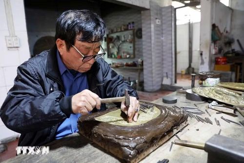 Nghệ nhân Đinh Quang Thắng (làng Đồng Xâm) khắc chạm thủ công bằng kỹ thuật tinh xảo. (Ảnh: Thế Duyệt/TTXVN)