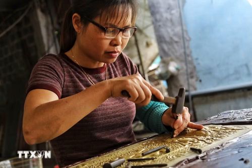 Người thợ tỉ mỉ chạm khắc từng đường nét trên tấm bạc, giữ gìn kỹ thuật thủ công truyền thống đã tồn tại hàng trăm năm. (Ảnh: Phương Anh/TTXVN phát)