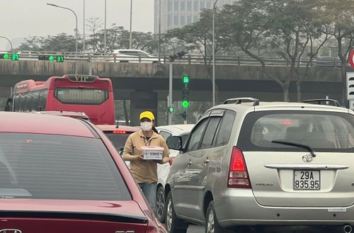 Người xin tiền len lỏi giữa các dòng phương tiện chờ đèn giao thông tại nút giao phố Bạch Thành phong - đường gom Đại lộ Thăng Long.