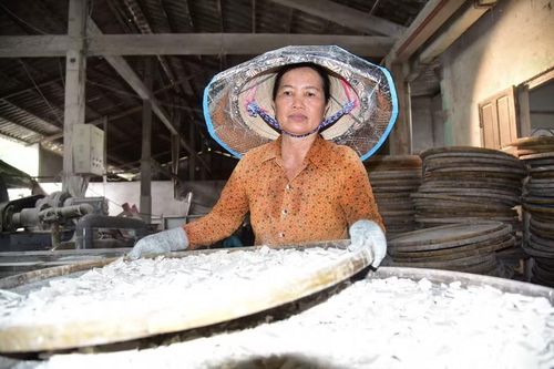 Chị Huỳnh Thị Hồng Nga hứng bột vào nia, dàn đều rồi đem phơi nắng. (Ảnh: Đức Hạnh/TTXVN)