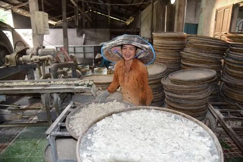 Chị Huỳnh Thị Hồng Nga hứng bột vào nia, dàn đều rồi đem phơi nắng. (Ảnh: Đức Hạnh/TTXVN)
