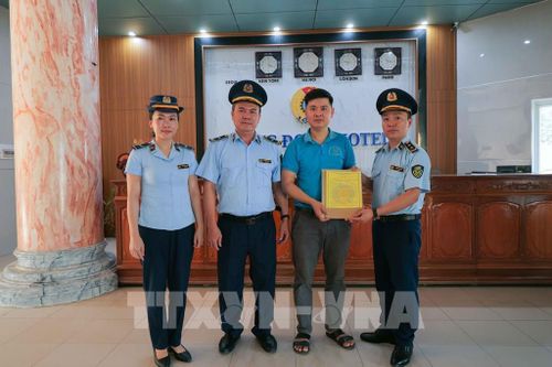 Đại diện Chi cục Quản lý thị trường Hà Tĩnh trao giấy cam kết minh bạch giá dịch vụ cho cơ sở lưu trú tại xã Thiên Cầm. Ảnh: Hữu Quyết – TTXVN