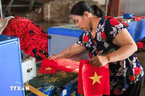 Vải được ép phẳng để tăng tính thẩm mỹ trước khi chuyển sang khâu may viền chắc chắn quanh mép cờ. (Ảnh: Lê Ngọc/TTXVN phát)
