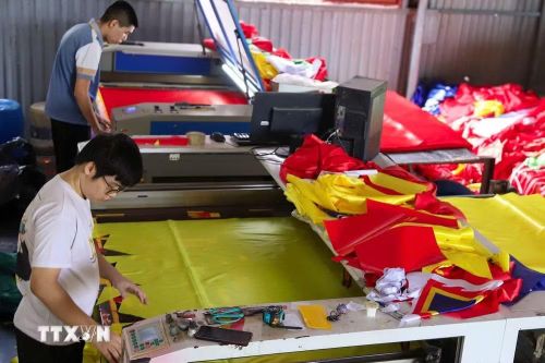 Mỗi lá cờ từ khâu cắt vải đến khâu in ngôi sao vàng hay biểu tượng búa liềm đều đòi hỏi độ chính xác cao đến từng chi tiết. (Ảnh: Lê Ngọc/TTXVN phát)
