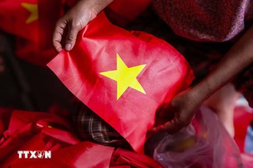 Người thợ kiểm tra lại từng sản phẩm, chỉnh sửa những chi tiết nhỏ nhất để đảm bảo mỗi lá cờ đều đạt chuẩn. (Ảnh: Lê Ngọc/TTXVN phát)