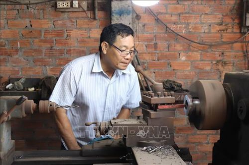 Anh Ngô Nguyên Hồng, người chế tạo ra máy vớt - cuộn lục bình, trong xưởng cơ khí của mình.