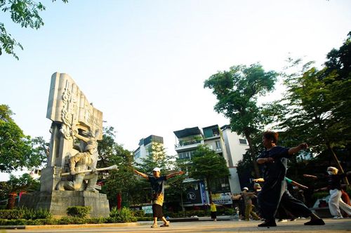 Những cụ bà tập thể dục trong không gian rộn ràng nhạc đỏ trước tượng đài “Quyết tử cho Tổ quốc quyết sinh” tại vườn hoa Vạn Xuân.