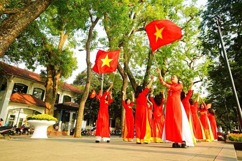 Nhóm phụ nữ trung niên trong tà áo dài đỏ, tay cầm cờ Tổ quốc, lan tỏa tinh thần yêu nước.