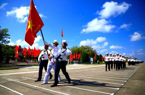 Hình ảnh các thành viên trong đoàn công tác cùng cán bộ, chiến sĩ và nhân dân trên đảo Trường Sa thực hiện nghi lễ thiêng liêng cùng lá cờ Tổ quốc.