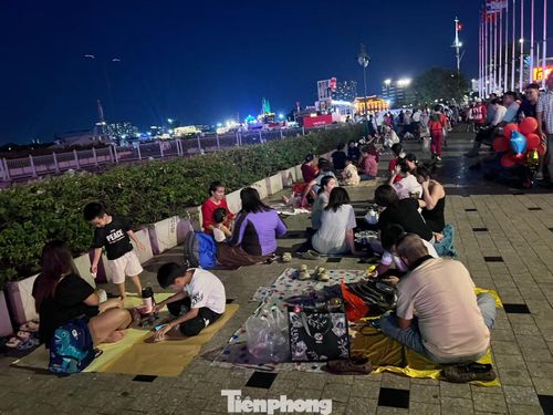 Tại các vị trí có thể ngắm pháo hoa đẹp nhất trên đường Tôn Đức Thắng, nhiều người tay xách nách mang đồ ăn, nước uống "xí chỗ" từ sớm