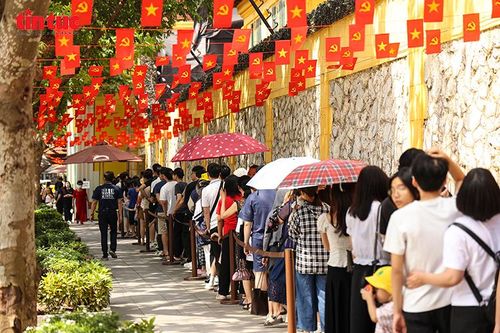 Nhiều em nhỏ xếp hàng trật tự dưới những tán cờ đỏ sao vàng bay phấp phới khi đến tham quan Nhà tù Hỏa Lò.